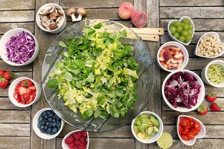 Diversi tipi di frutta, verdura, funghi e frutta secca su un tavolo