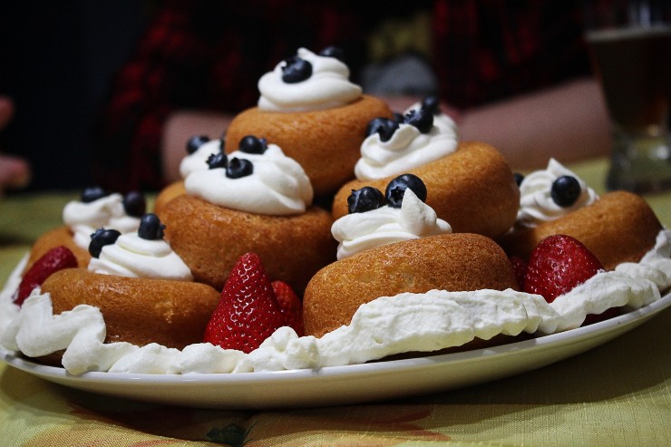 Babà rivisitati con frutti di bosco, fragole e panna su un piatto