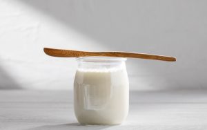 Vasetto di yogurt e cucchiaio di legno su un tavolo