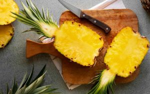 Ananas tagliata a metà su un tagliere accanto a un coltello